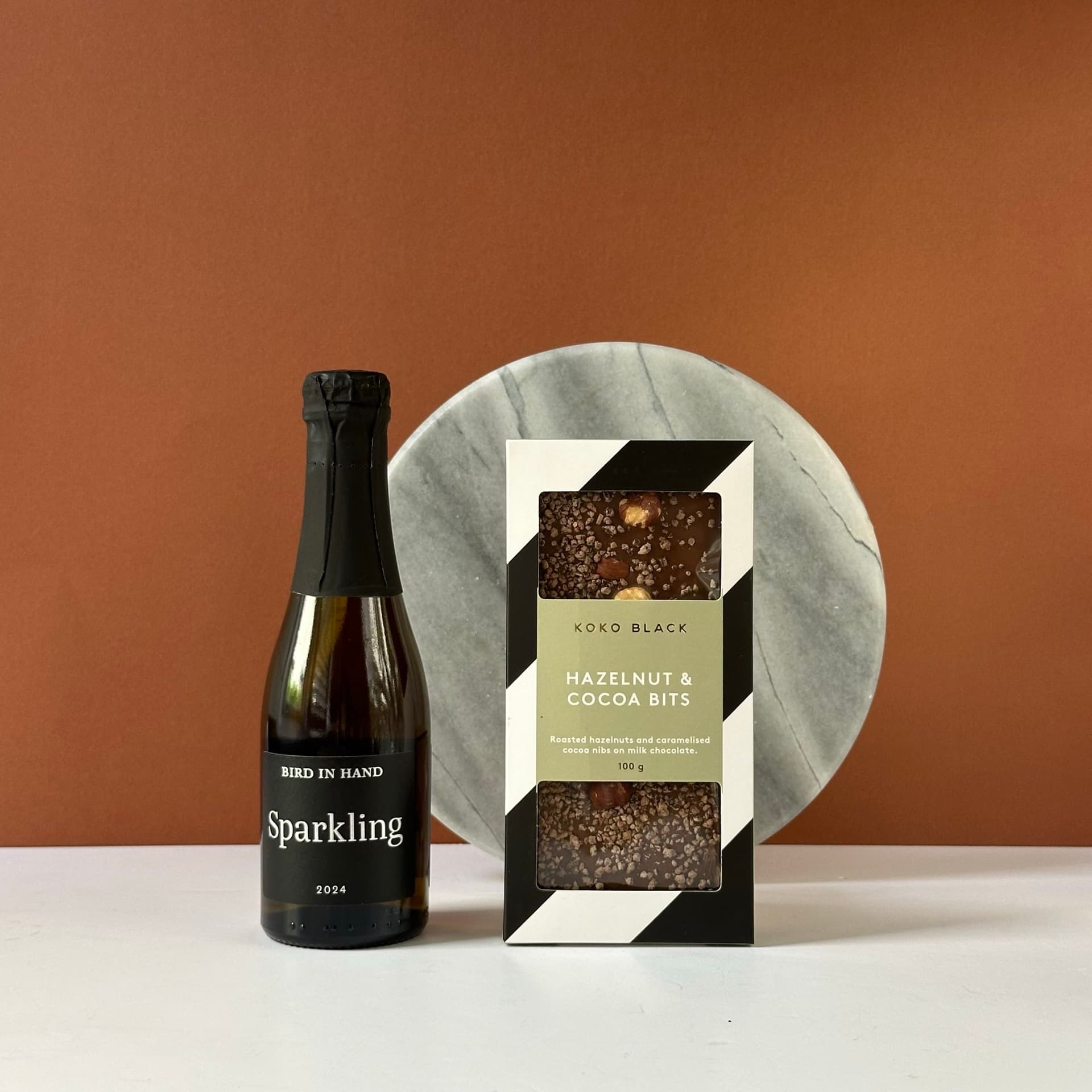 Bird in Hand Sparkling Mini Bottle 200ml – A refreshing sparkling wine with vibrant bubbles and a delicate finish. Koko Black Hazelnut & Cocoa Bits Chocolates 100g – Gourmet milk chocolate with crunchy hazelnut and cocoa bits.