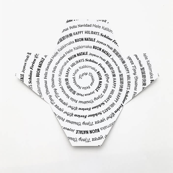 Signature Thankly Happy Holidays envelope, with Happy Holidays written in different languages in a spiral pattern